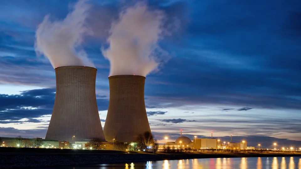 A nuclear power station at dusk with steam rising from its cooling towers